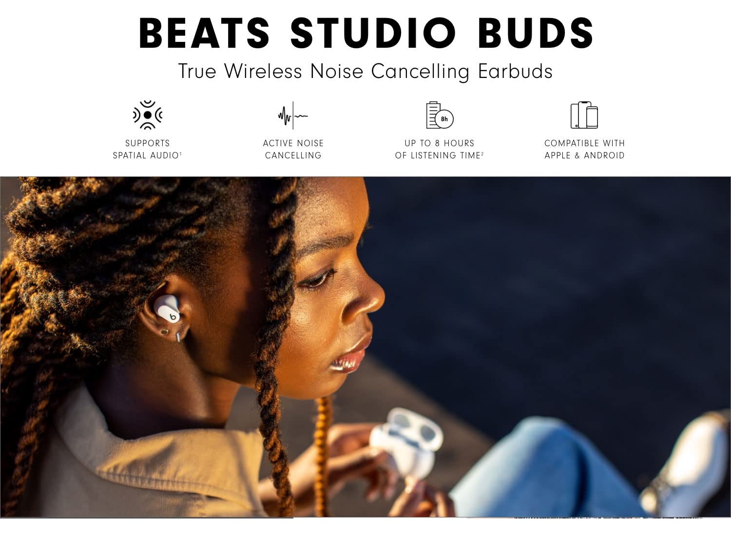 دختر جوان با هدفون Beats Studio Buds سفید در گوش در حال گوش دادن به موسیقی